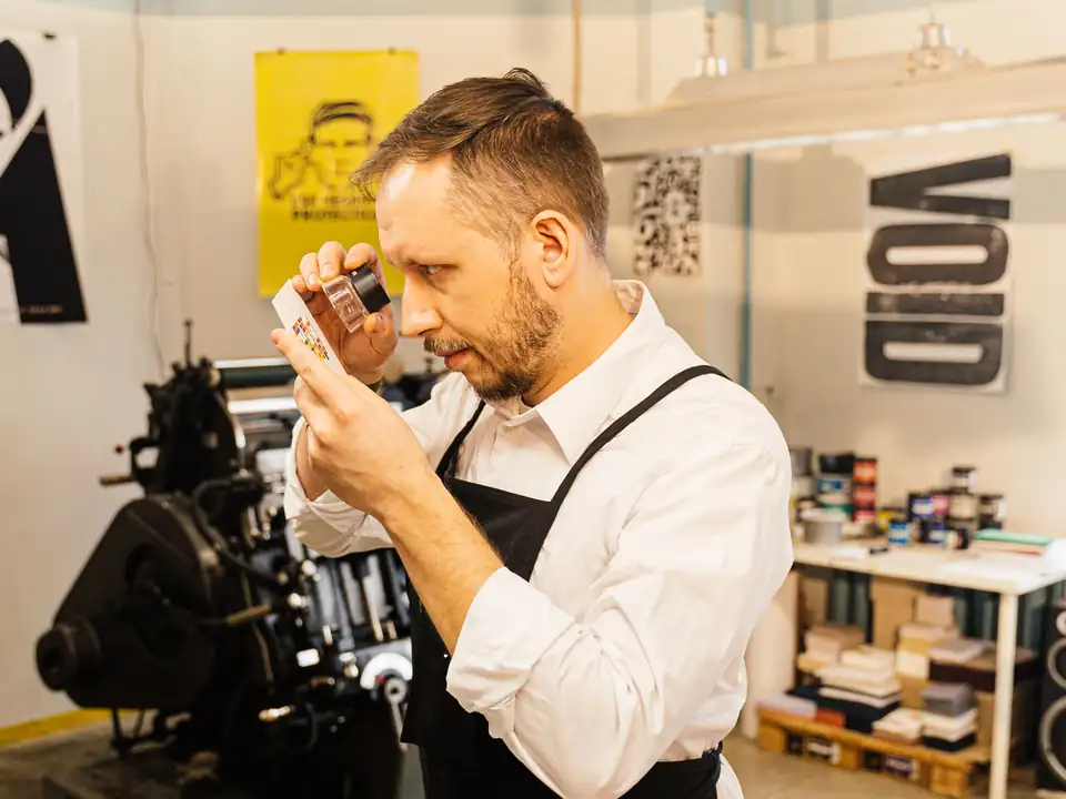 A printmaker checking a physical color proof in a studio